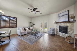 Tiled living area featuring ceiling fan, a fireplace, and french doors