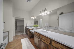 Bathroom featuring two vanities, stone finish flooring, and a spacious closet