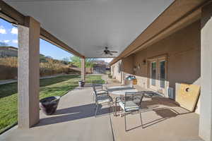 Fenced backyard with a patio, outdoor dining area, and a ceiling fan