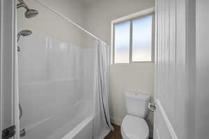 Full bath featuring toilet and shower / tub combo with curtain