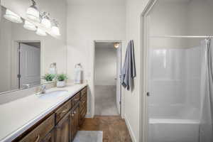 Bathroom with stone finish flooring, vanity, shower / tub combo, and a ceiling fan