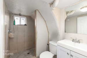 Bathroom featuring vanity, a textured ceiling, and tiled shower