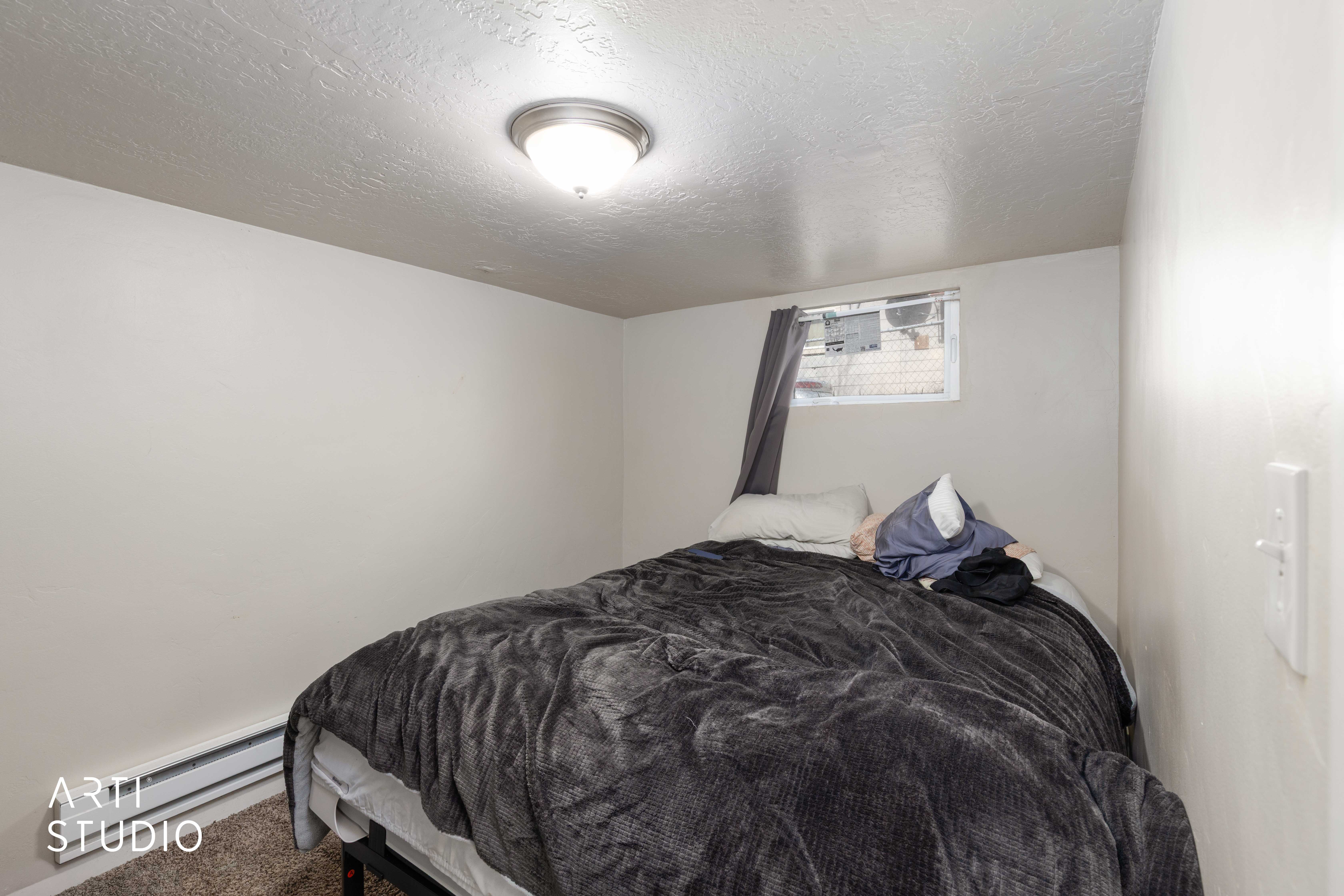 Carpeted bedroom with a textured ceiling and baseboard heating