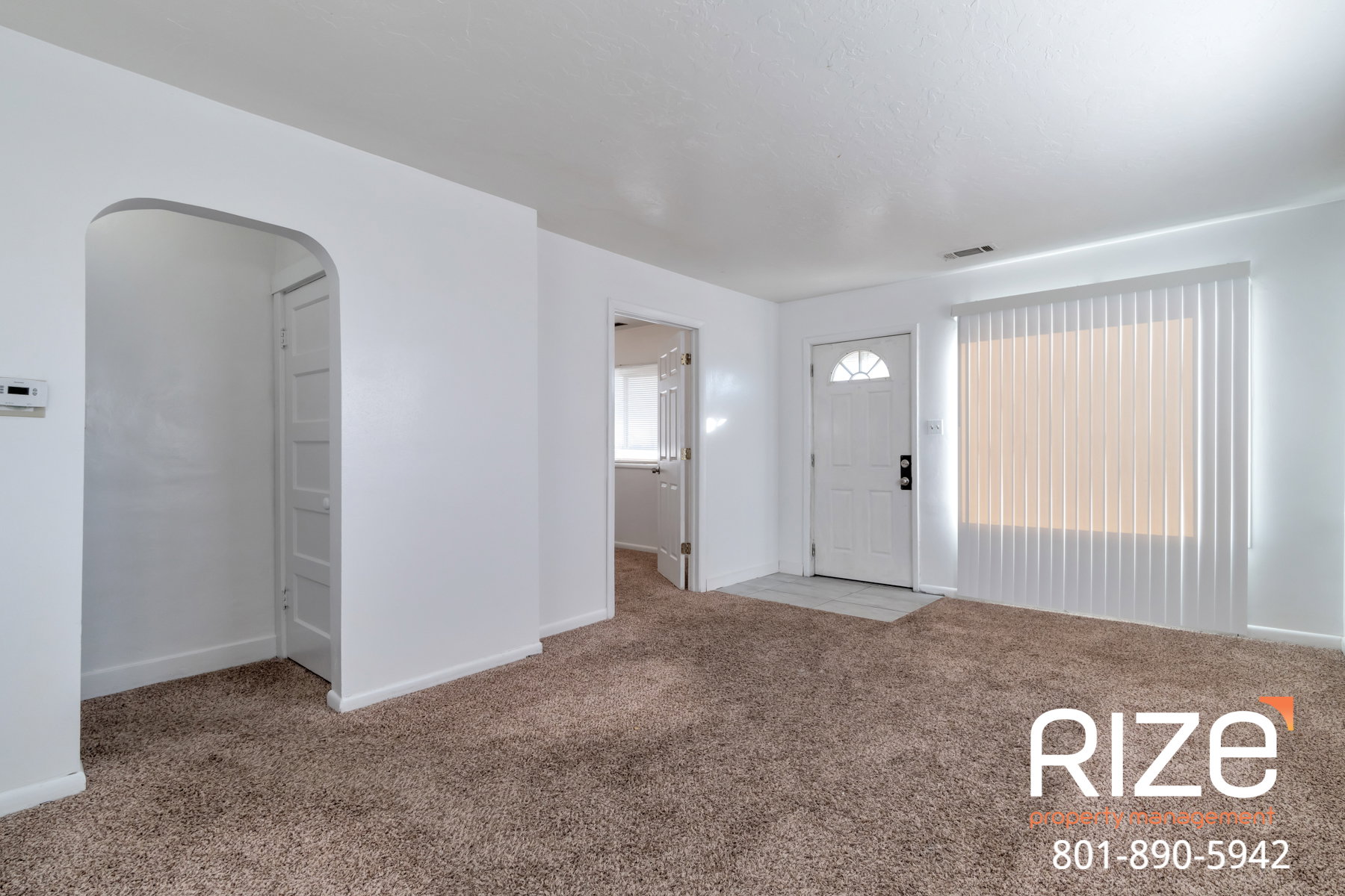 Entrance foyer with arched walkways and light colored carpet
