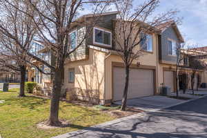Traditional-style home with a garage, stucco siding, driveway, and a front lawn