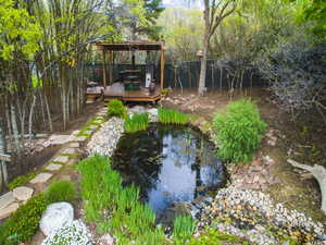 Fenced backyard with a small pond, a wooden deck, and a gazebo