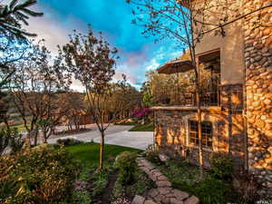 Yard at dusk with a balcony and a lawn