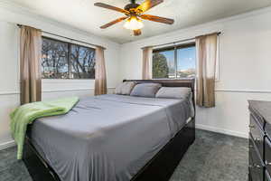 Bedroom featuring dark carpet, a textured ceiling, ceiling fan, and crown molding