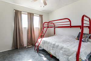 Bedroom with carpet floors, a ceiling fan, and a textured ceiling