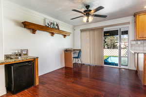 Dining space with ceiling fan, dark wood-type flooring, ornamental molding, and a textured ceiling