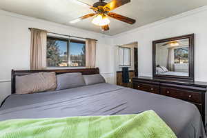 Bedroom featuring a textured ceiling, a ceiling fan, and crown molding