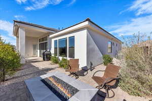 Rear view of house with an outdoor fire pit, a patio area, and stucco siding