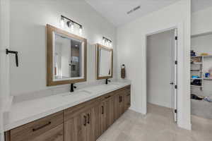 Full bath featuring double vanity, a spacious closet, and light tile patterned floors