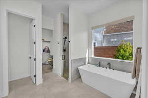 Bathroom featuring a shower stall, a freestanding tub, and tile walls