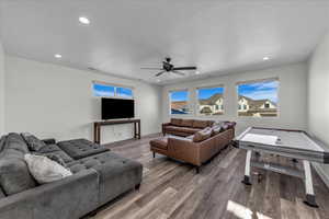 Living room with wood finished floors, recessed lighting, a ceiling fan, and a textured ceiling