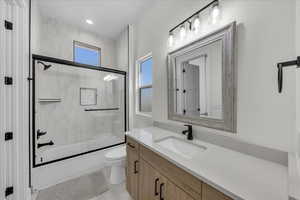 Full bathroom featuring vanity and shower / bath combination with glass door