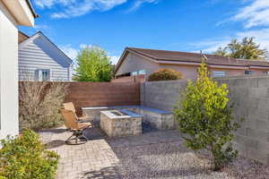 Fenced backyard featuring a fire pit and a patio area