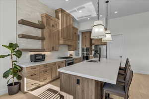 Kitchen featuring open shelves, light stone countertops, pendant lighting, tasteful backsplash, and an island with sink