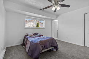 Carpeted bedroom featuring baseboard heating, a textured ceiling, and a ceiling fan