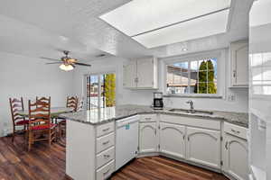 Kitchen featuring a peninsula, dark wood-type flooring, white appliances, a textured ceiling, and white cabinetry