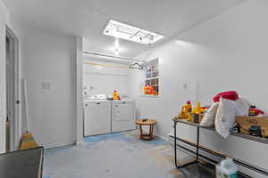 Laundry area featuring baseboard heating, concrete floors, independent washer and dryer, and a textured ceiling
