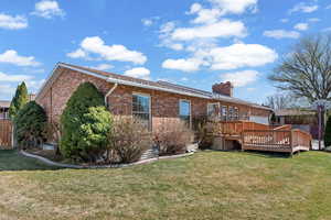 Rear view of property with a deck, brick siding, and a chimney