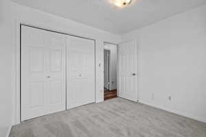 Unfurnished bedroom featuring carpet, a textured ceiling, and a closet