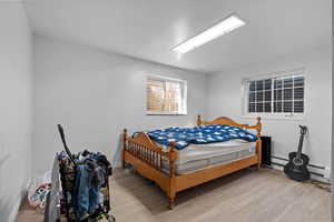 Bedroom featuring light wood-style floors, a textured ceiling, and a baseboard radiator
