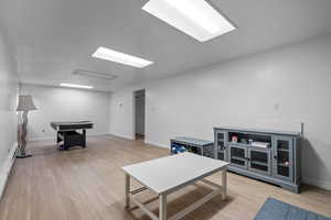 Recreation room featuring light wood-style flooring and a baseboard radiator