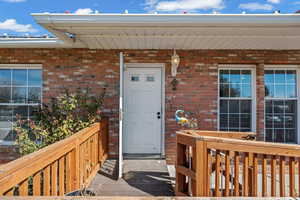 Property entrance featuring brick siding and a deck