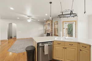 Kitchen featuring dishwasher, open floor plan, arched walkways, a ceiling fan, and light wood-style floors