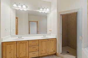 Bathroom featuring double vanity, a stall shower, and light tile patterned flooring