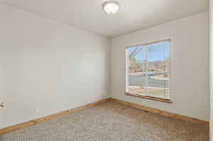 Unfurnished room featuring light carpet and baseboards