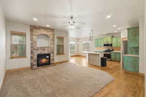 Kitchen featuring green cabinetry, open floor plan, a kitchen island, stainless steel appliances, and light countertops