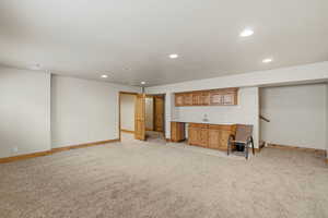 Unfurnished living room with wet bar, light carpet, and recessed lighting