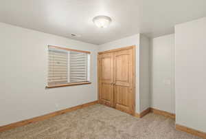 Unfurnished bedroom with light carpet and a closet