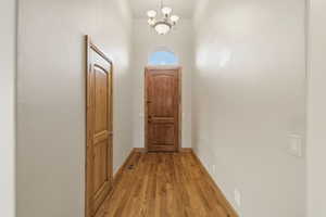 Doorway with wood finished floors and a chandelier