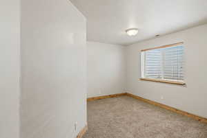 Spare room featuring light colored carpet and baseboards