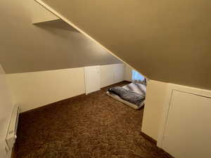 Bonus room with dark colored carpet and lofted ceiling