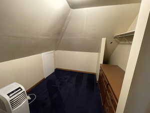 Walk in closet featuring dark carpet, lofted ceiling, and heating unit