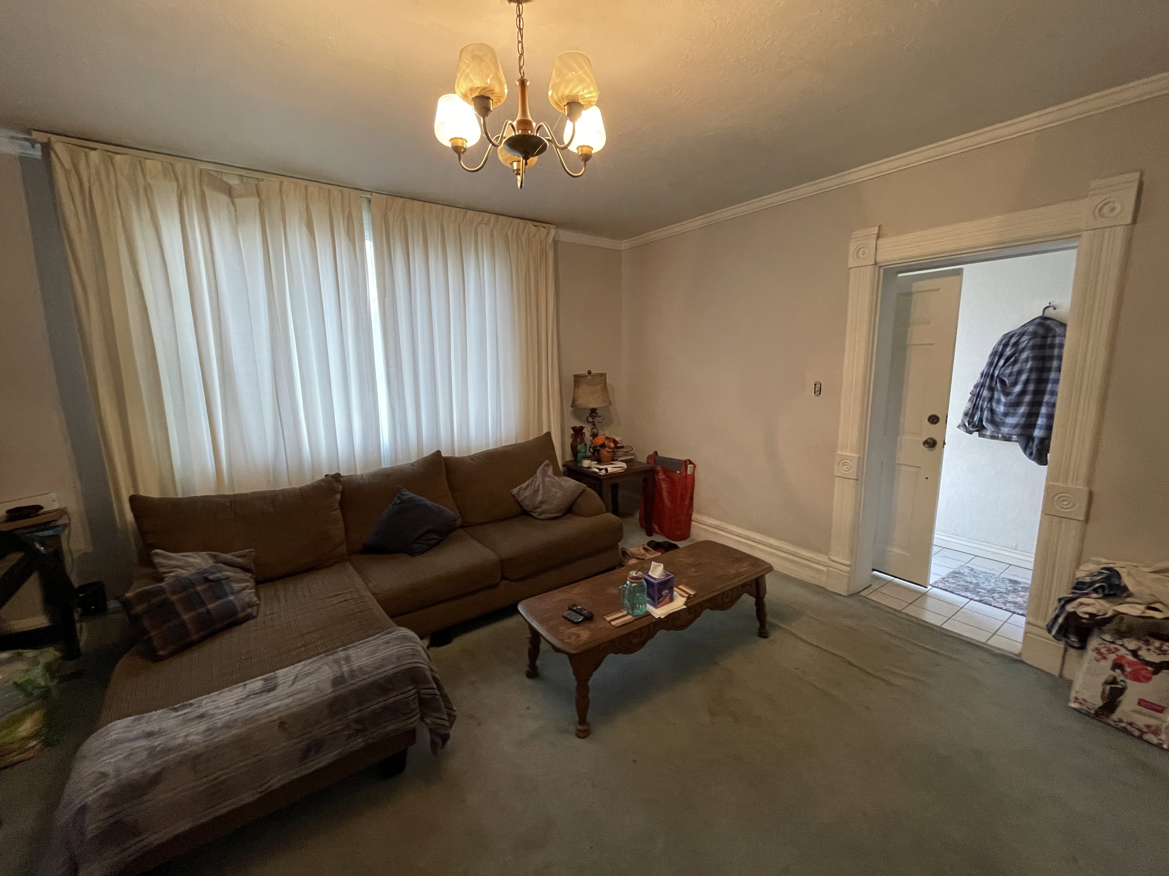 Carpeted living area featuring suspended lighting and ornamental molding