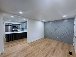 Unfurnished dining area featuring an accent wall, a decorative wall, recessed lighting, and light wood finished floors