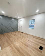 Spare room with light wood-style floors, recessed lighting, an accent wall, and a smoke detector