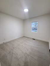 Empty room with light colored carpet and baseboards