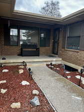Doorway to property with a porch and brick siding