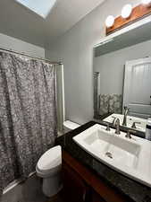 Full bathroom #1 with vanity, a textured ceiling, a skylight, and shower / bathtub combination