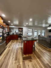 Kitchen featuring a textured ceiling, stainless steel appliances, an island with sink, and open floor plan