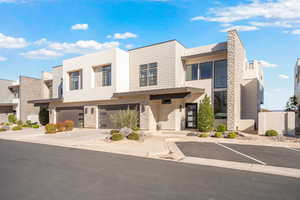 Contemporary home featuring stone siding, stucco siding, and a garage