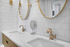Full bath with double vanity, tile walls, and decorative backsplash