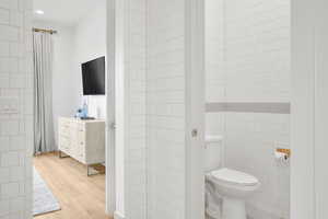 Bathroom with tile walls, light wood-style floors, and vanity